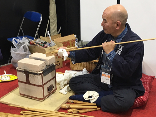 Yasuo Nakadai straightening bamboo using heat from small gas stove and bricks