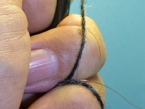 Holding yarn and wire tight by wrapping wire around ring finger and yarn around little finger.