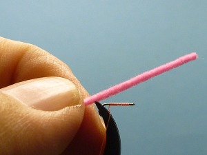 Pink thread wrapped on hook shank to form body. Chenille held in place prior to tying in.