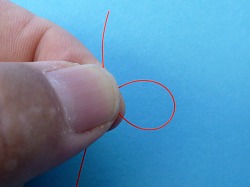 Thumb and forefinger holding a loop of line.