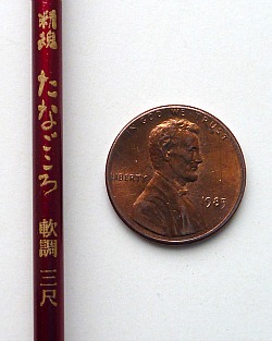 Nissin Tanago Koro alongside penny for scale. The handle section of the rod is very narrow.