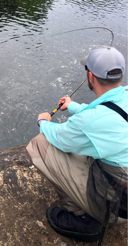 Angler holding rod with deep bend caused by fish on the line
