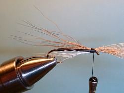 Properly positioned on top of shank, brown bucktail tied in tightly.