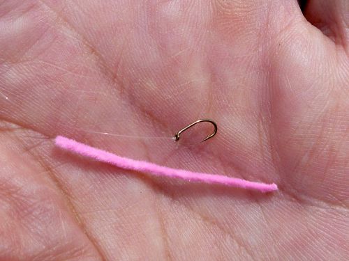 Cut length of chenille and a hook in angler's palm.