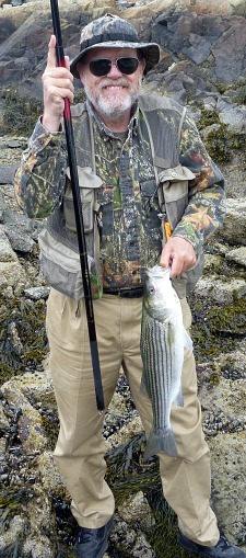 Angler holding a carp rod and a striped bass