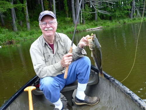 Fishy sitting in a canoe, holding a bass