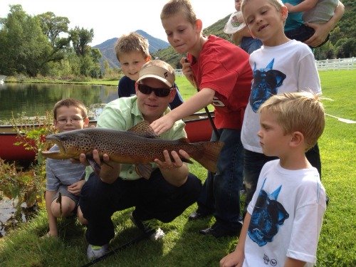 Slilde: Photo of angler holding large trout, surrounded by young boys