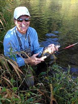 Angler holding trout and a Nissin Zerosum tenkara rod