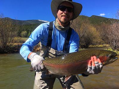Jared K holding huge trout with river and mountains in background