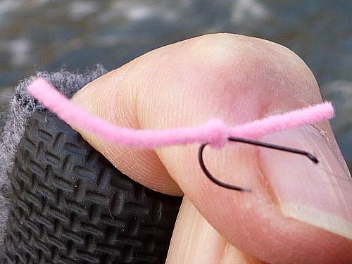 Overhand worm hooked lightly in angler's finger.