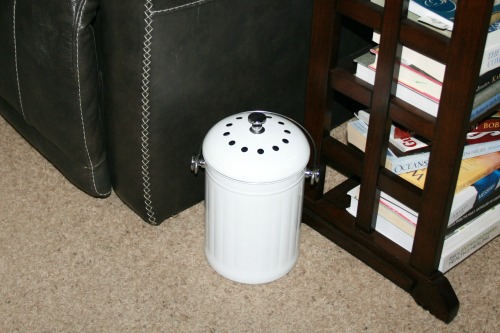 White pail in a living room by chair and small bookshelf.