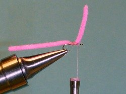 Lift end of chenille, and tie whip finish on bare shank, under chenille.