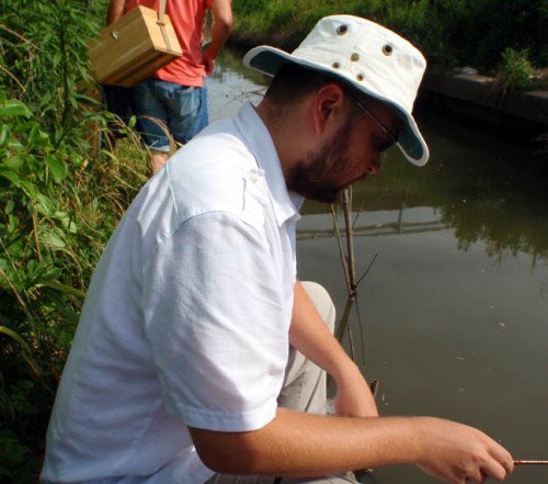 Angler sitting at water's edge.